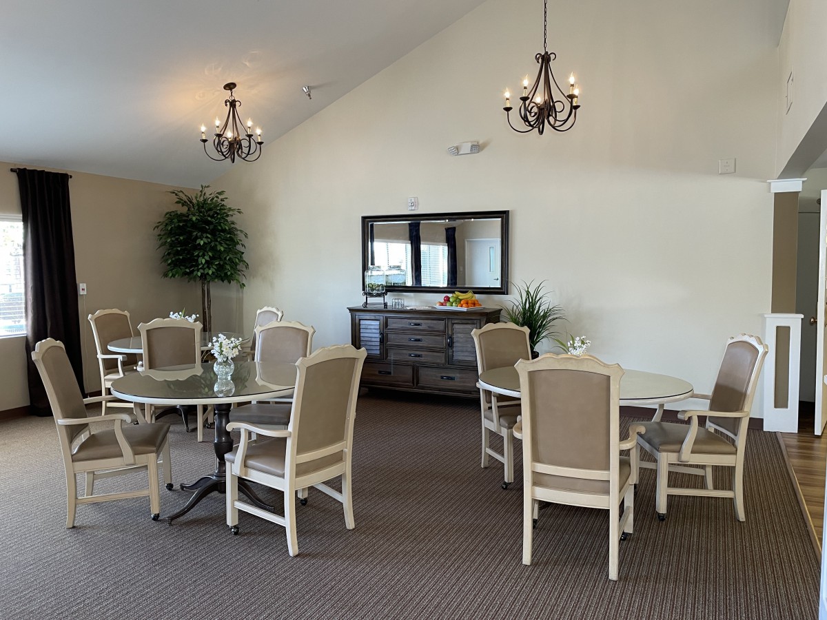 A well-decorated dining room featuring round tables, upholstered chairs, and elegant chandeliers.