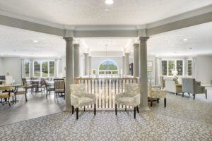 A modern and elegantly designed living room with columns, comfortable seating, and ample natural light from large windows.