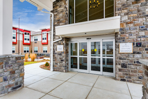 A modern building entrance featuring sliding glass doors and a stone exterior.