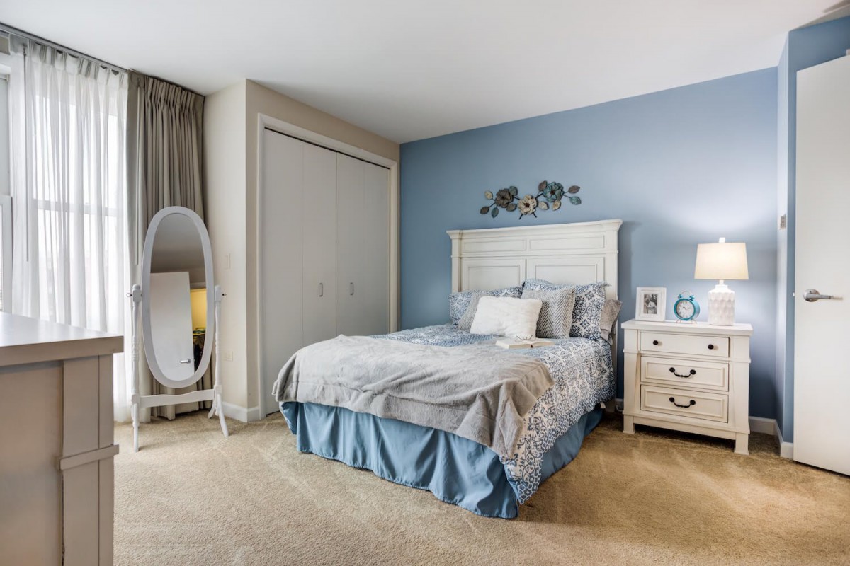 A cozy bedroom with a white bed, blue accent wall, and elegant decor.