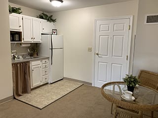 Minimalist kitchen area in an apartment with white cabinets and a small dining table.