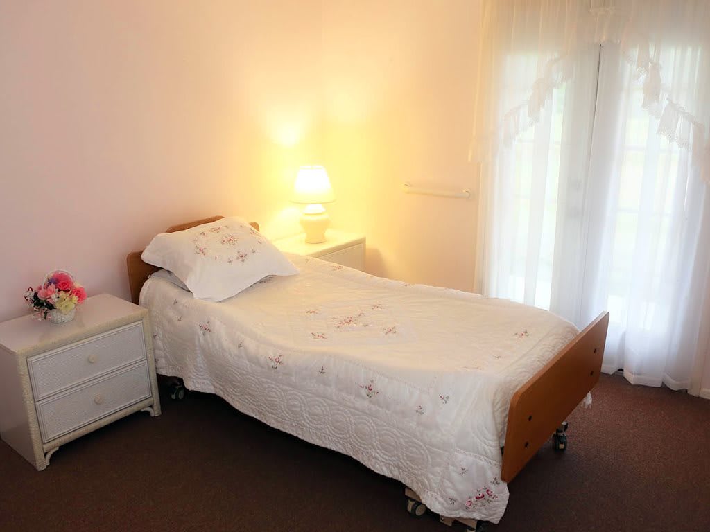 A cozy bedroom with a single bed and a softly lit lamp.