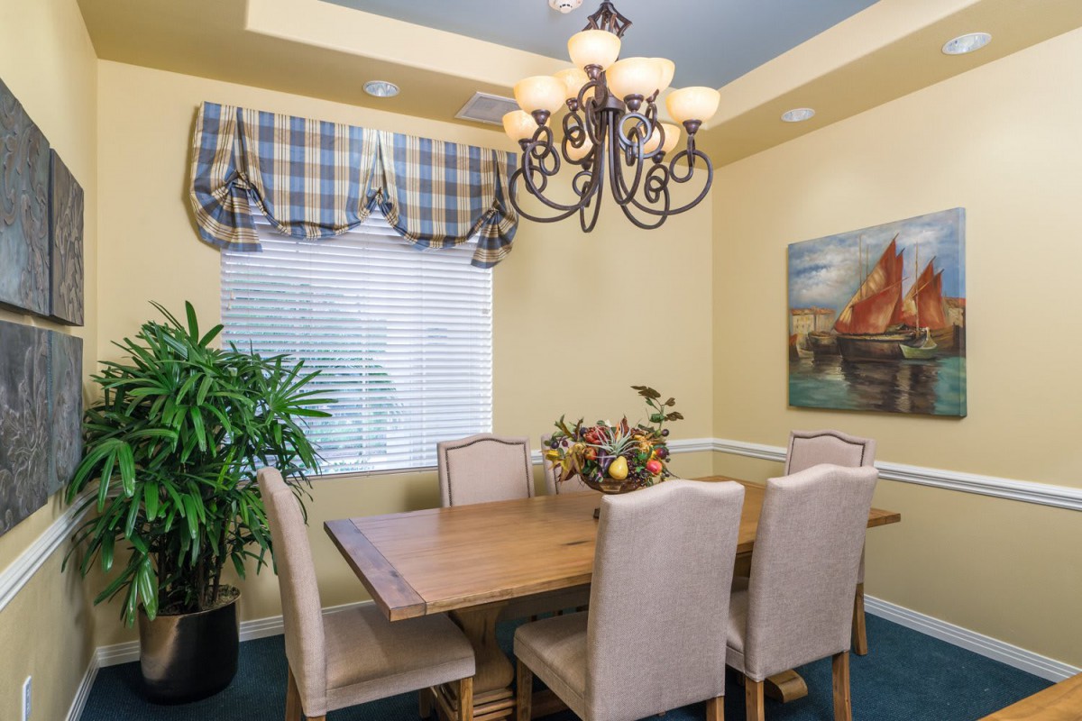 A cozy dining room with a wooden table, six chairs, and a decorative chandelier.