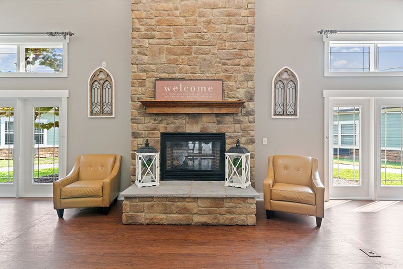A cozy living room featuring a stone fireplace flanked by two leather armchairs and decorative lanterns.