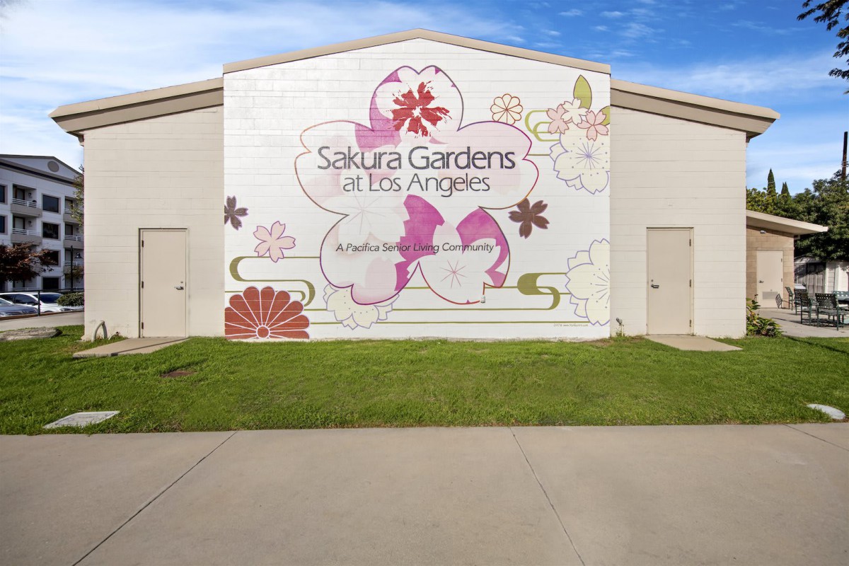 A mural on a building displaying floral designs and the text 'Sakura Gardens Los Angeles'.