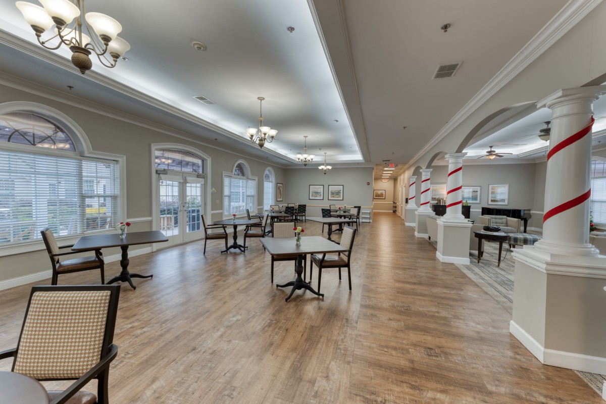 An elegant dining area with hardwood floors, tables, and chandeliers.