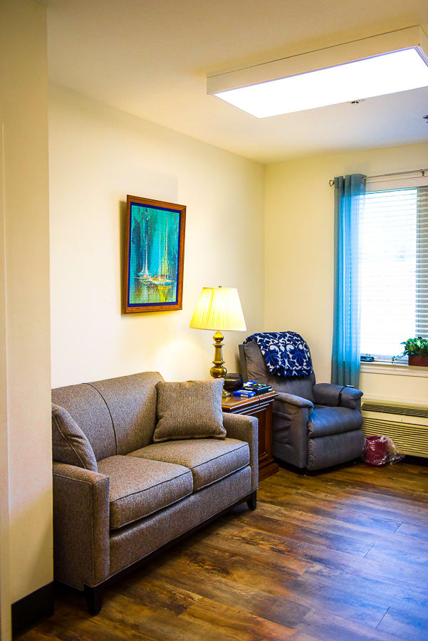 A cozy living room with a sofa, armchair, and a lamp by the window.