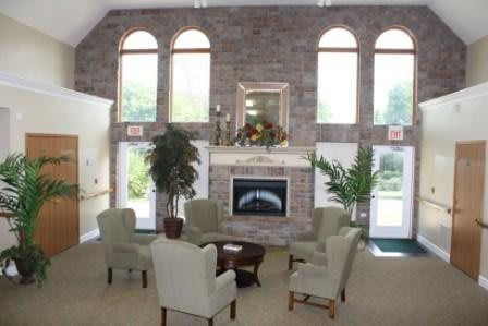 A cozy lounge area featuring a brick wall with a fireplace, surrounded by comfortable chairs and decorative plants.