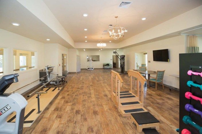 A well-equipped fitness room featuring treadmills and exercise areas on a wooden floor.