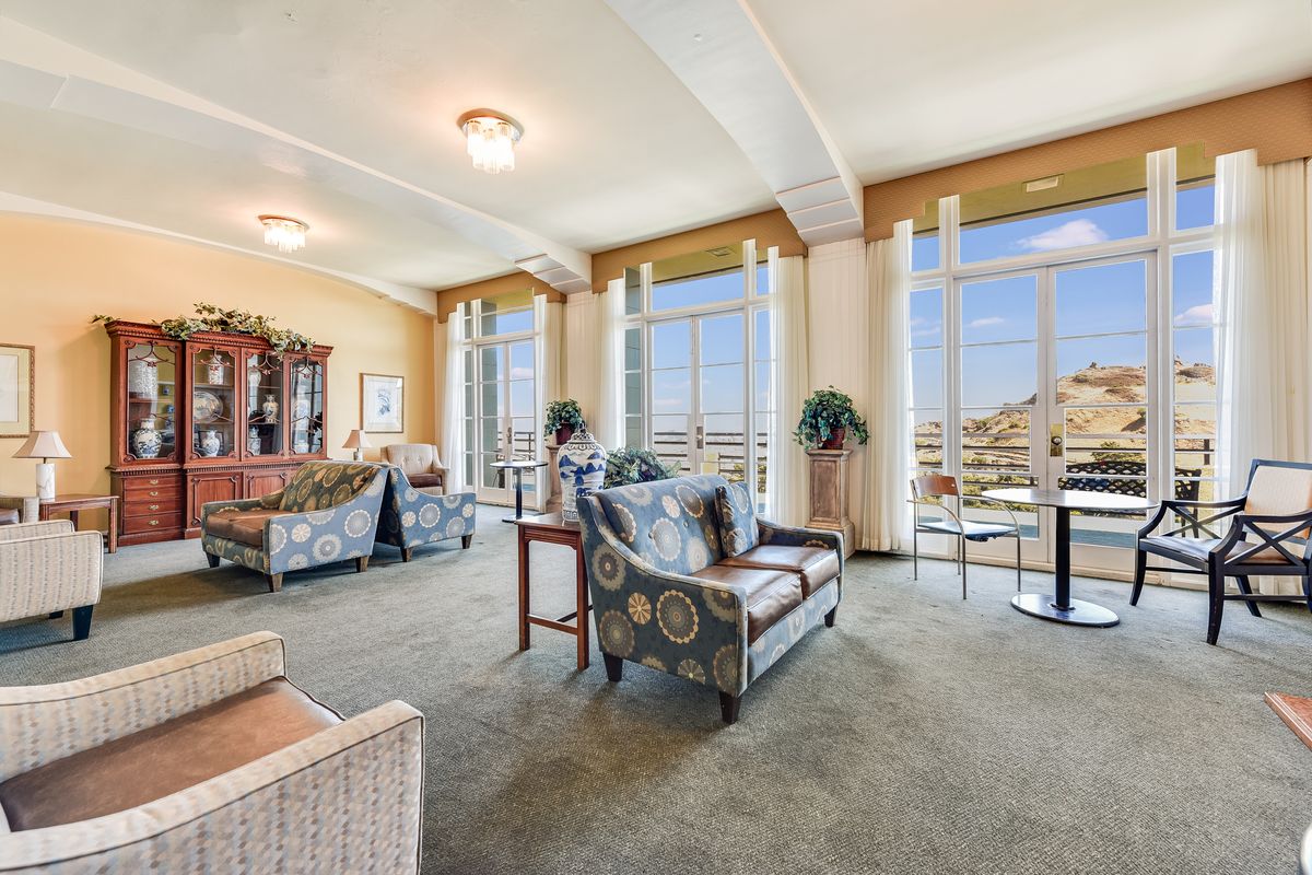 A spacious living room with large windows, allowing ample natural light to fill the space, featuring comfortable seating and elegant decor.
