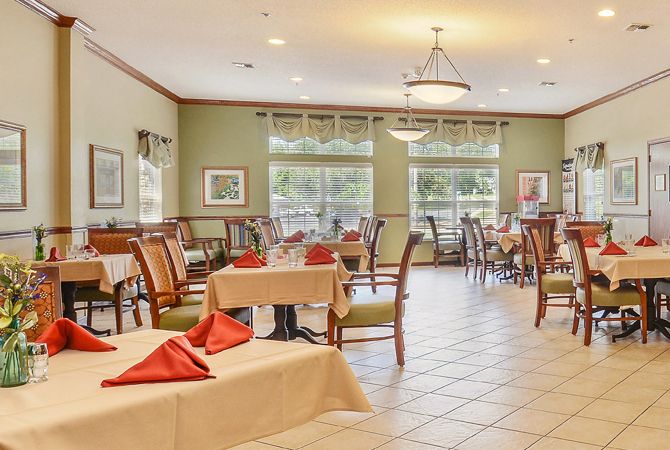 A well-lit dining area with neatly arranged tables and chairs, set with tablecloths and napkins.