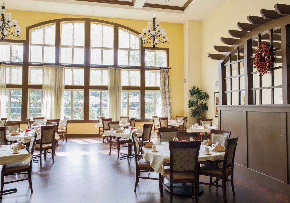 A well-lit dining area with large windows and elegantly set tables.