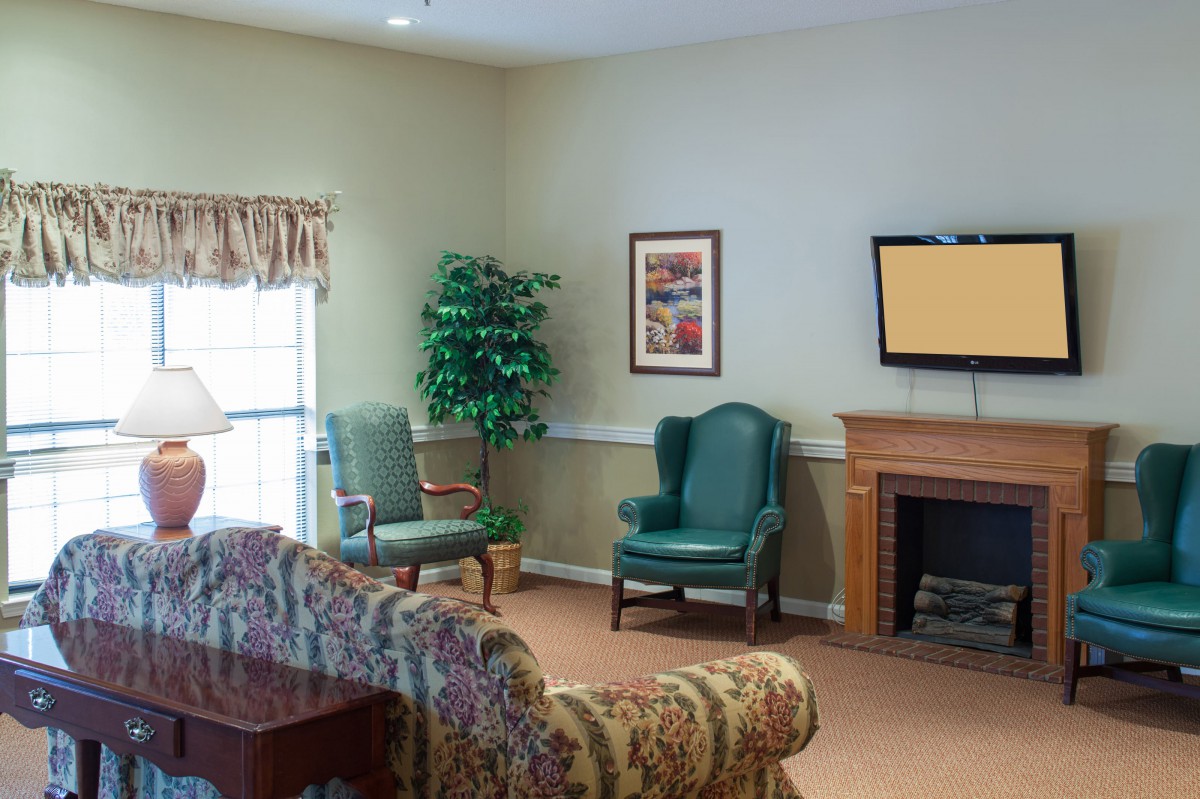 A cozy living room with armchairs, a patterned sofa, and a fireplace.