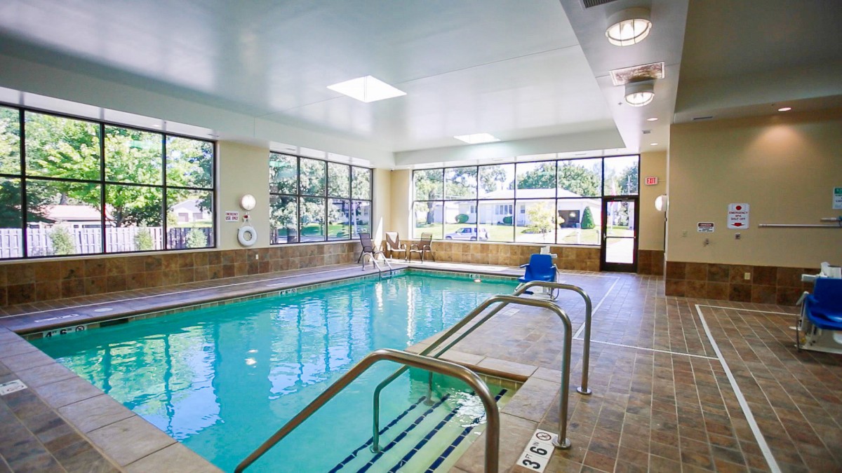 An indoor swimming pool with large windows and a seating area, offering a relaxing atmosphere.