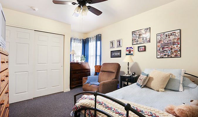 A cozy bedroom with a bed, armchair, and decorative items on the walls.