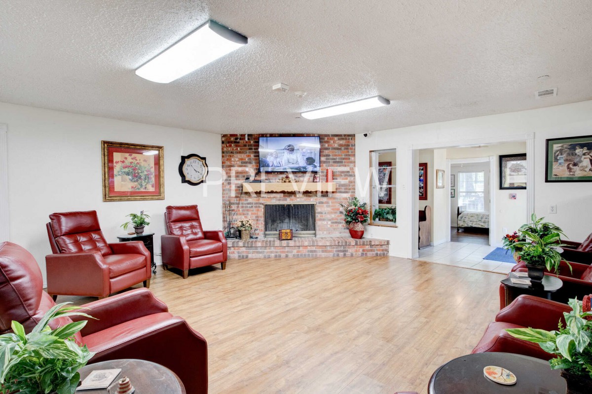 A cozy living room featuring a brick fireplace, modern recliner chairs, and a TV mounted above the mantle.