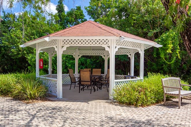 A charming gazebo with patio furniture set in a lush garden.