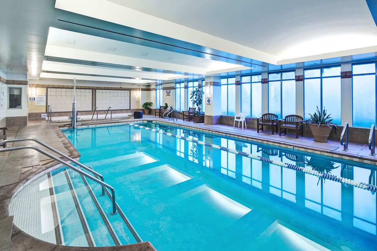 A spacious indoor swimming pool with lounge chairs and large windows.