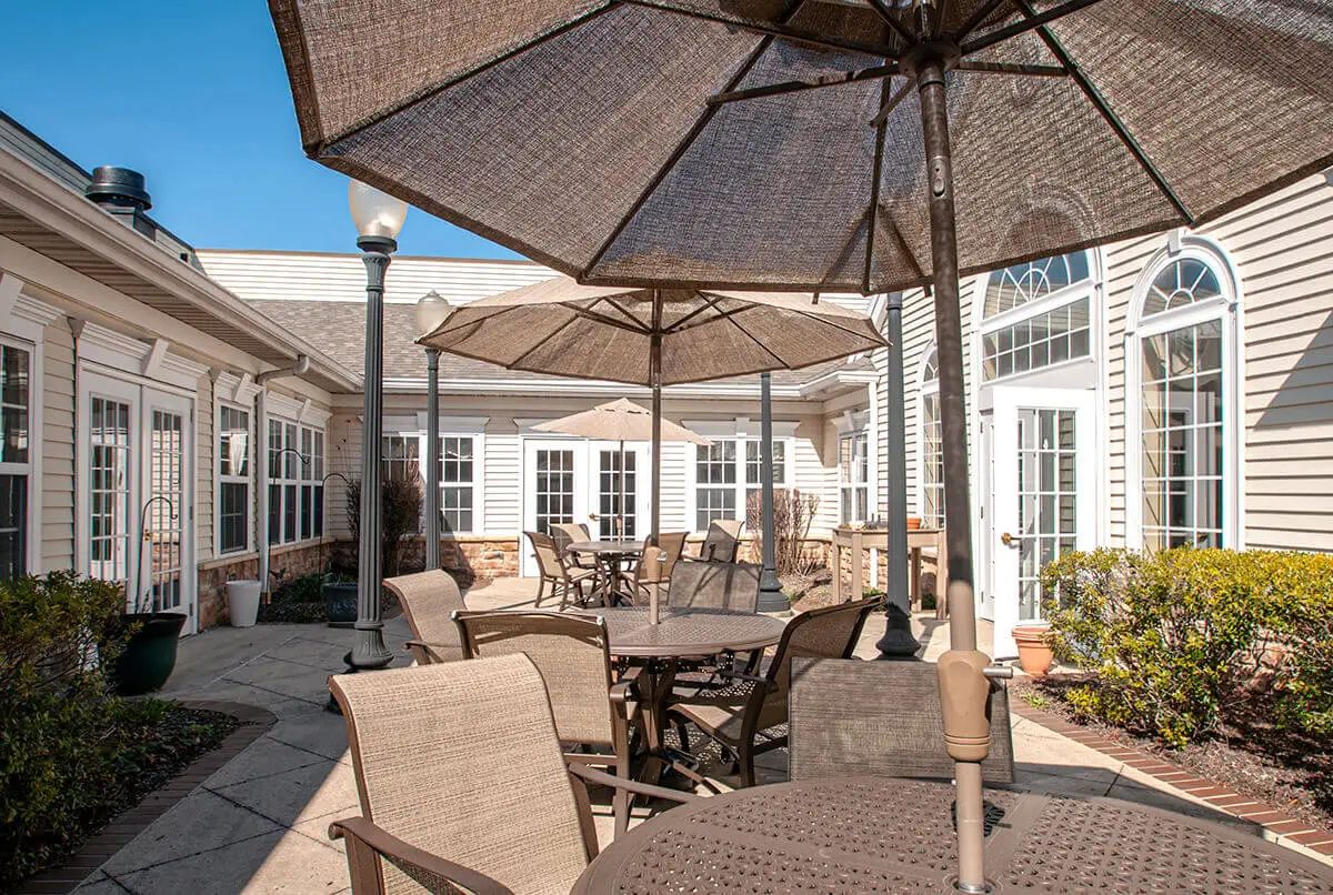 A cozy outdoor patio with tables and chairs under large umbrellas on a sunny day.