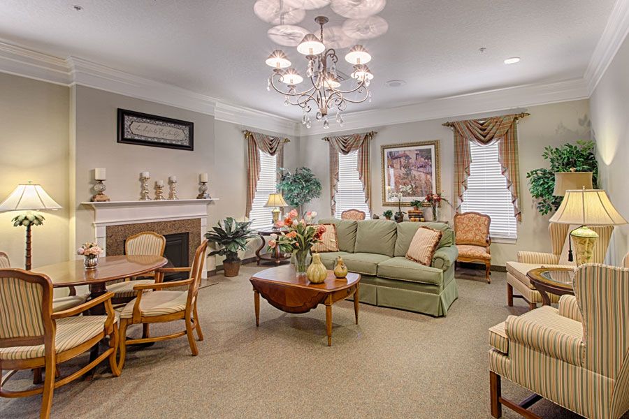A traditionally styled living room featuring a comfortable sofa set, a fireplace, elegant chandelier, and tasteful decor.