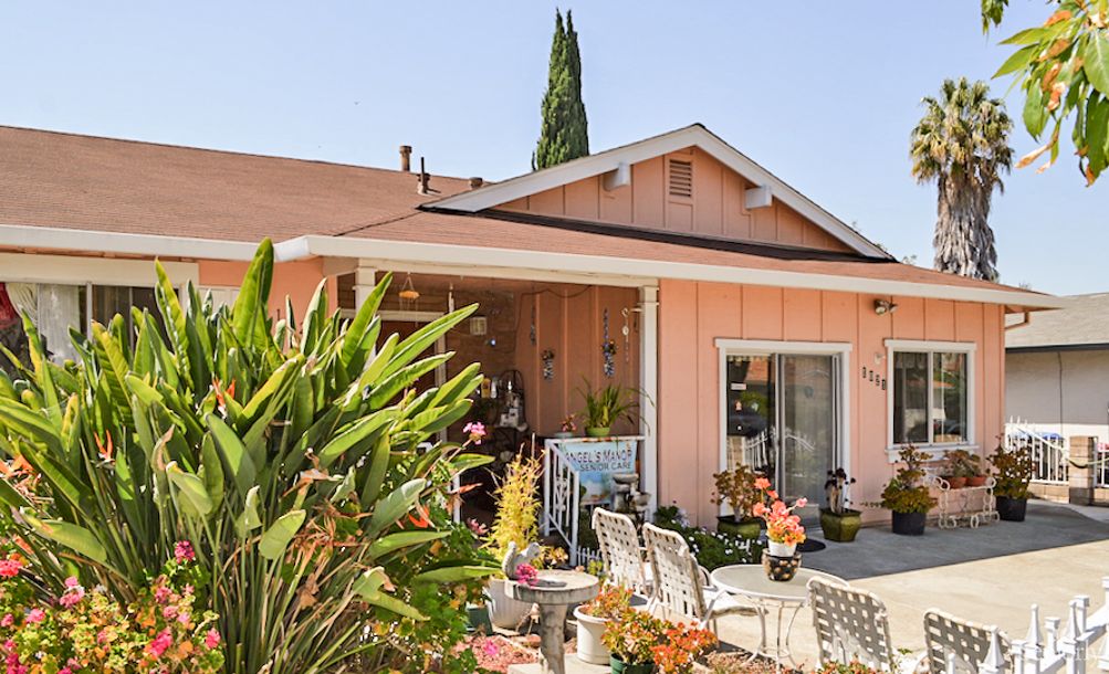 A charming pink house with a garden and outdoor seating area.