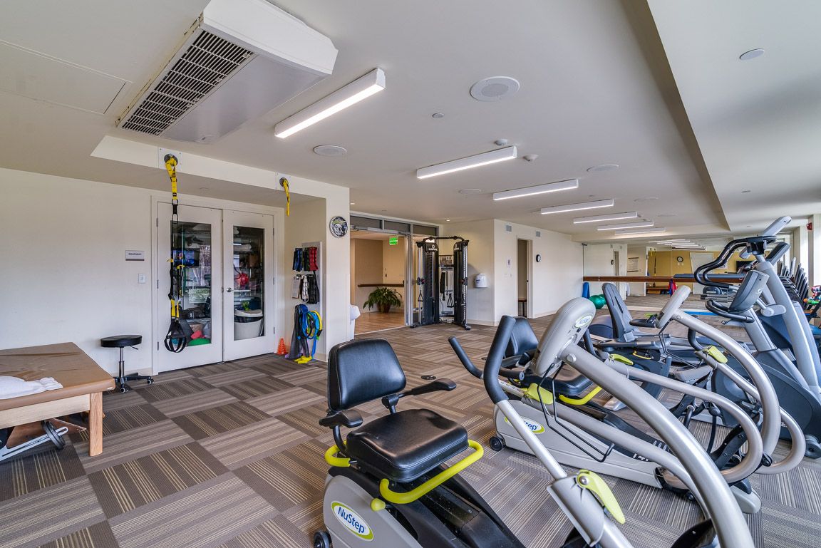A modern gym interior featuring various exercise equipment and bright lighting.