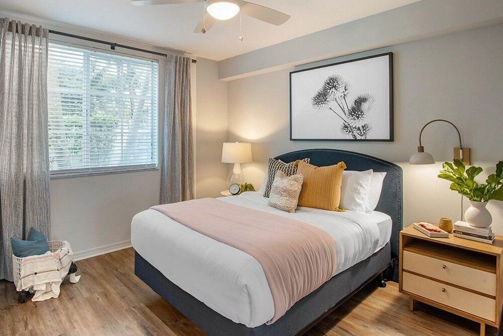 A cozy and modern bedroom with a neatly made bed, stylish artwork, and warm lighting.