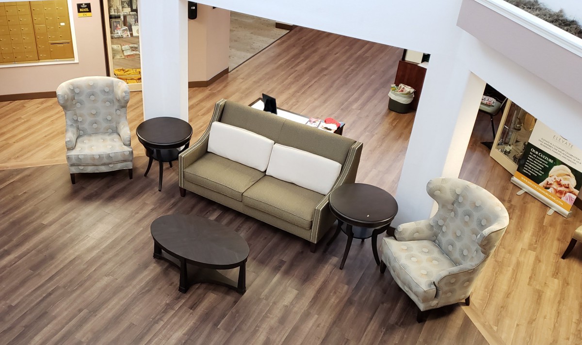 A cozy living room setup with a sofa, two round tables, and an armchair on a wooden floor.