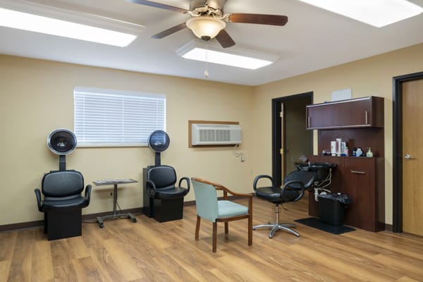 An empty salon interior with chairs and hairdryers.