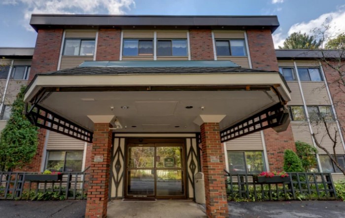 The image shows the entrance of a brick building with large windows above.