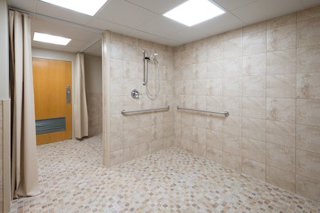 An accessible shower room with handrails and a tiled floor.