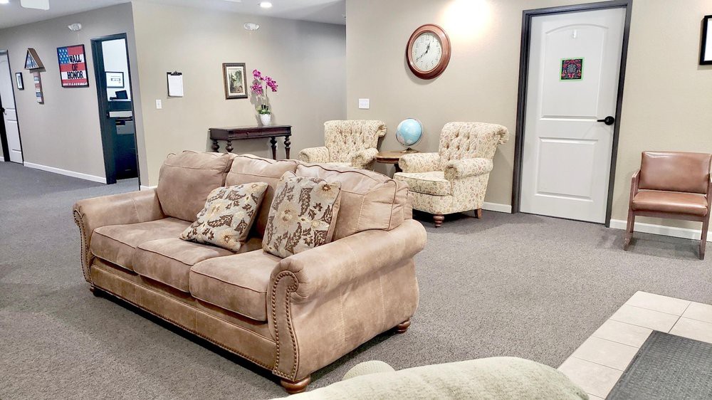 A cozy living room with a sofa, armchairs, and decorative elements like a globe and wall clock.
