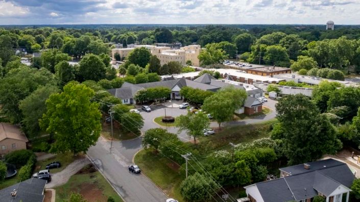 Aerial view of a suburban area with buildings, roads, and lush greenery.