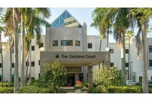 The entrance of The Gardens Court hotel surrounded by palm trees.
