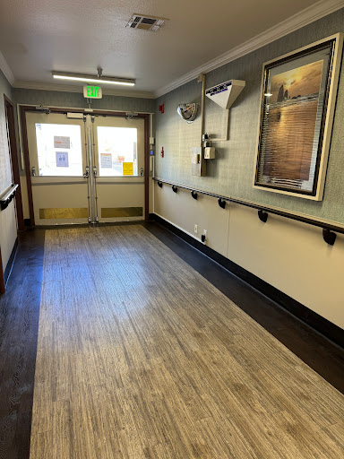 A well-lit hallway featuring two doors at the end and visible handrails along the walls.