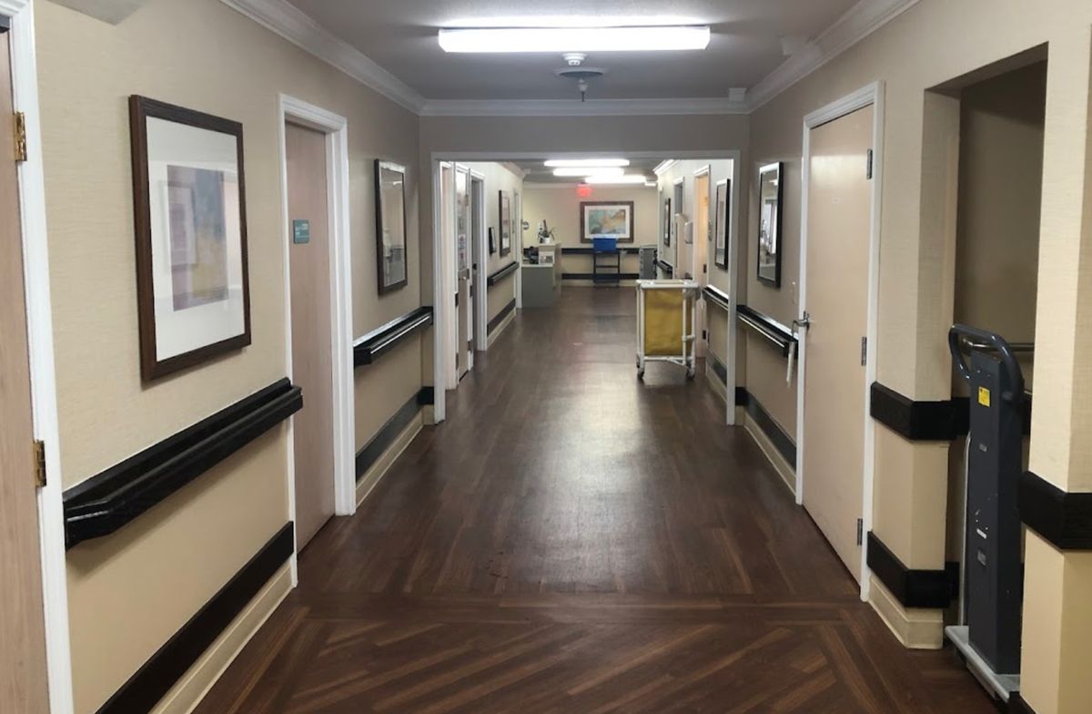 A well-lit hospital corridor lined with doors and handrails.