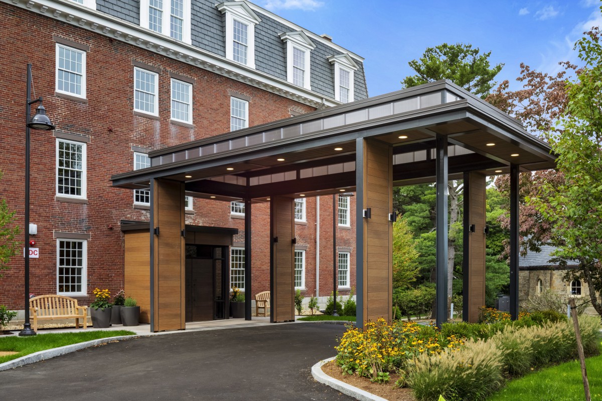 A modern hotel entrance with a brick exterior and landscaped surroundings.