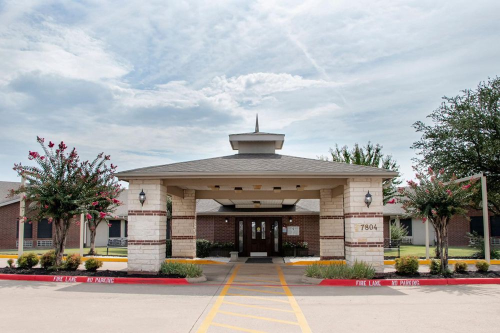 A covered entrance to a building with a cloudy sky overhead.