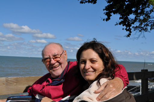 A joyful moment shared between an elderly man and a woman, smiling together with a scenic background.