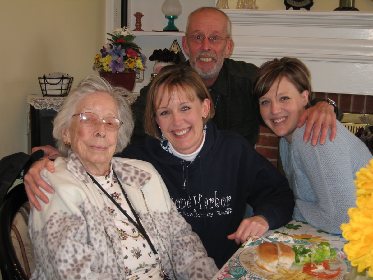 A family gathering with four people smiling together indoors.