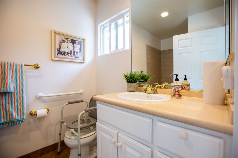 A neatly arranged bathroom with a sink, mirror, and toilet featuring simple decor.