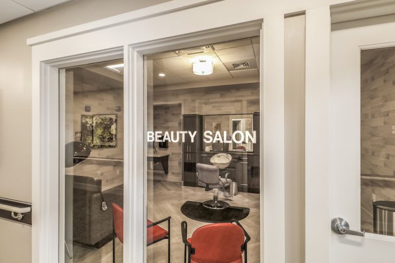 A view into a beauty salon through a glass door, featuring chairs and stylish interior design.