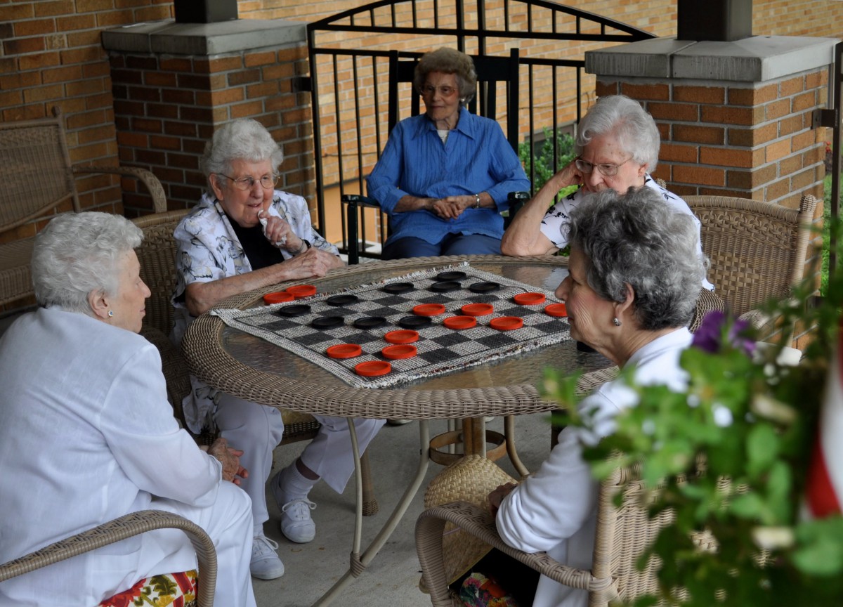 A group of elderly women enjoying a game of checkers outdoors.
