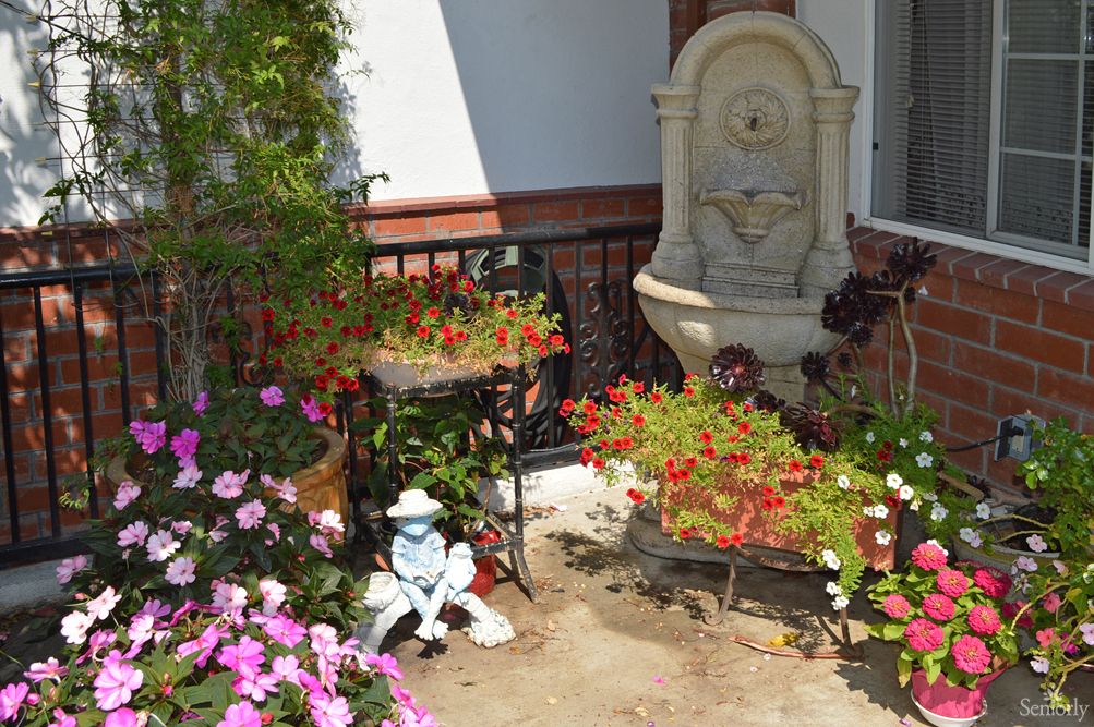 A charming garden corner with colorful flowers, a decorative fountain, and a garden ornament.