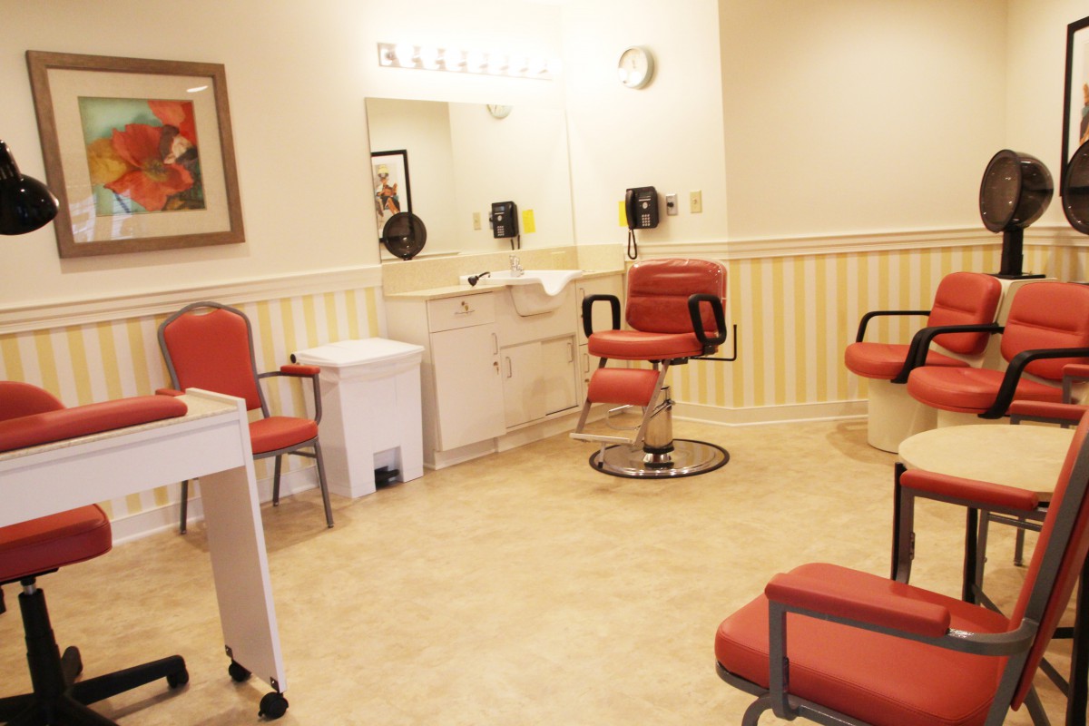 An interior view of a hair salon with red chairs and mirrors.