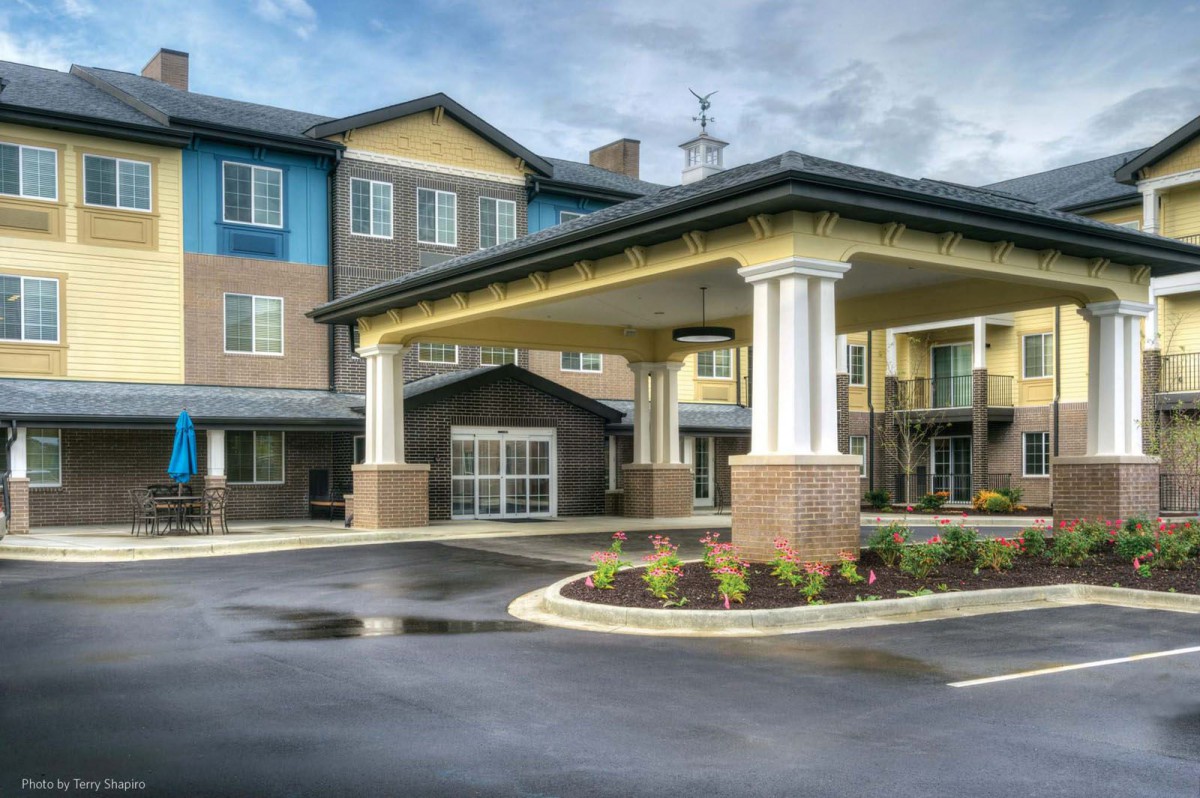 The entrance of a modern commercial building featuring columns and a covered driveway.