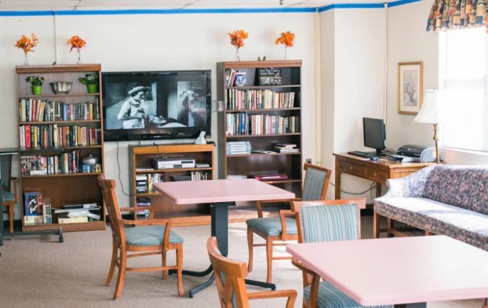 A cozy communal room with a television, bookshelves, and seating area.