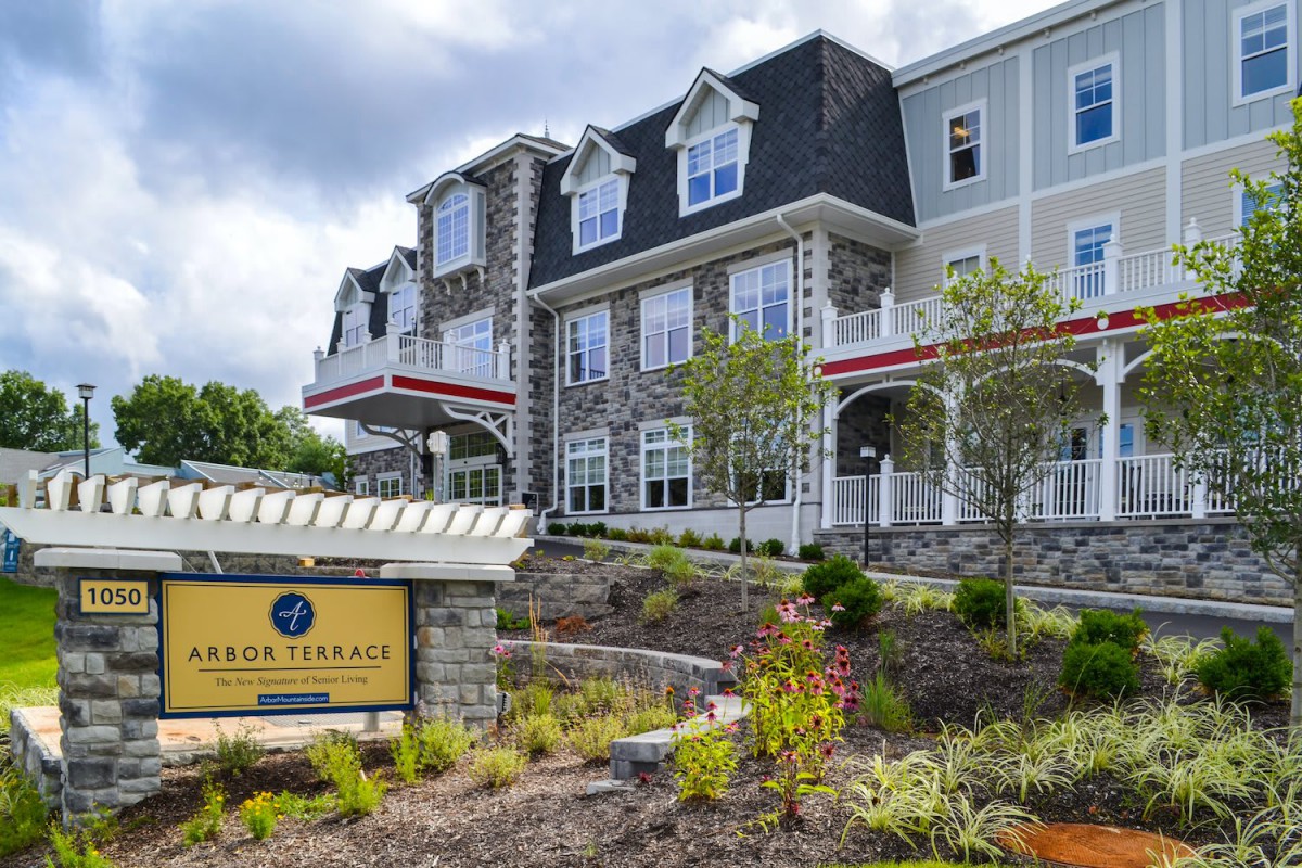 A modern residential building with a stone facade and landscaped surroundings.