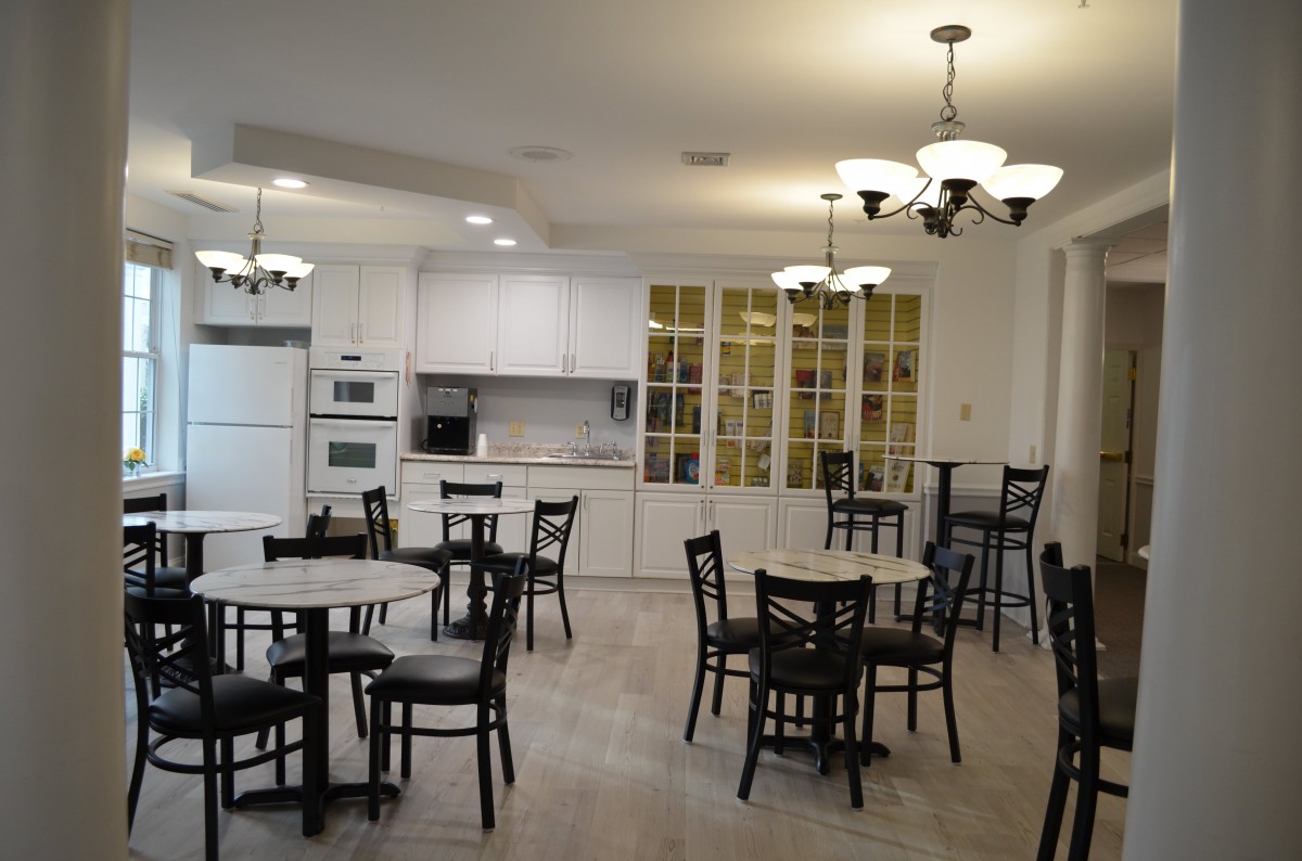 A modern kitchen and dining area with tables, chairs, and overhead lighting.