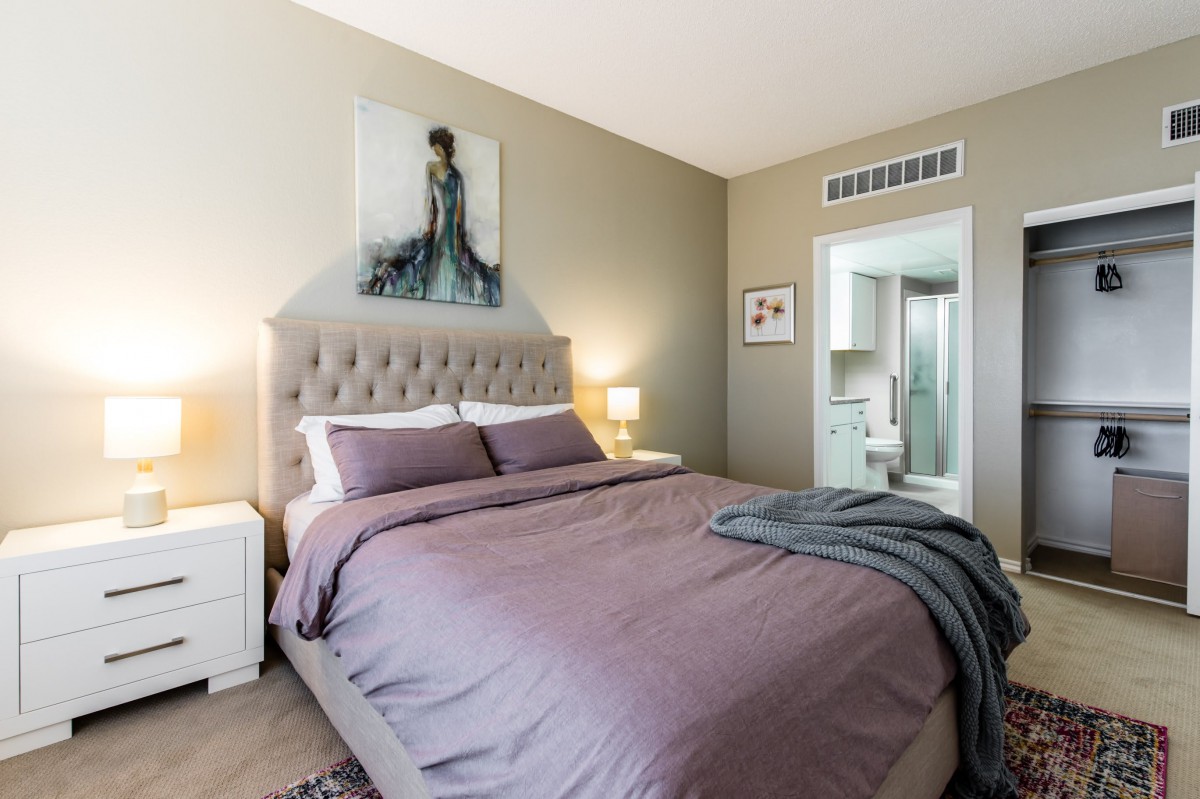 A cozy and elegant bedroom with a large bed, soft lighting, and tasteful artwork.
